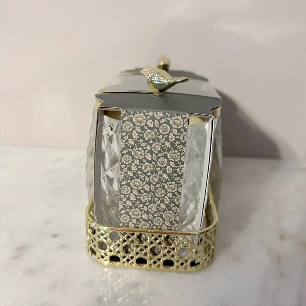 two-piece glass storage jar set with a gold bird lid and decorative tray.
